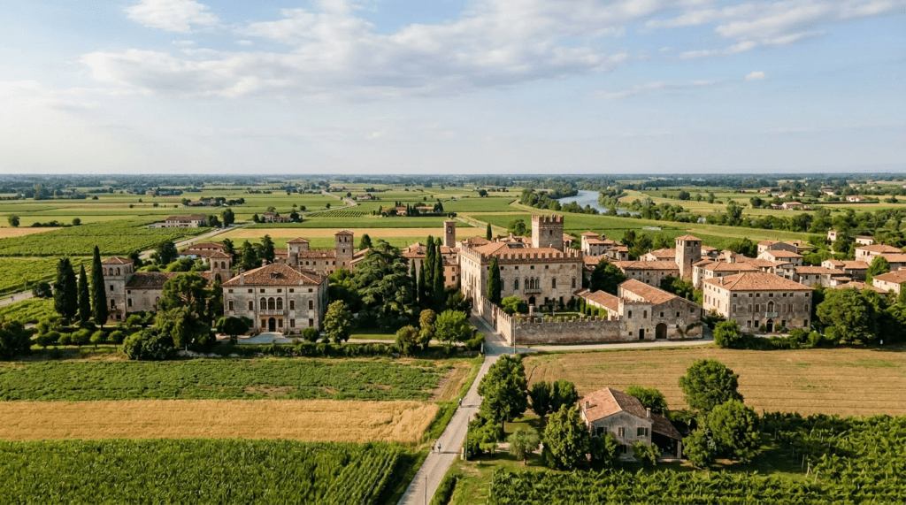 Historic estate with multiple buildings and towers in a green valley with mountains
